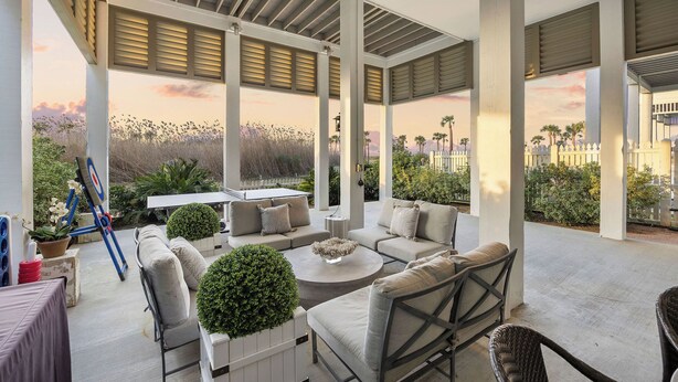 Un patio al aire libre con zona de estar, incluyendo sofás y una mesa de centro, rodeado de plantas y vistas del paisaje.