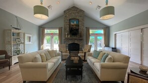 A spacious living room with two beige sofas, a black coffee table, and a stone fireplace. - Seaglass Village Wells #426.Near Clubhouse. Same Time Next Year Promotion, NOW! (Wells)