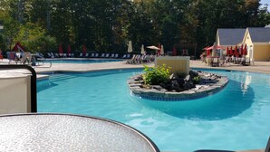 A swimming pool with lounge chairs and umbrellas, surrounded by trees and a building. - Seaglass Village Wells #426.Near Clubhouse. Same Time Next Year Promotion, NOW! (Wells)