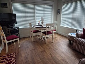 A living room with a TV, dining table, chairs, and a sofa. - Seaglass Village Wells #426.Near Clubhouse. Same Time Next Year Promotion, NOW! (Wells)