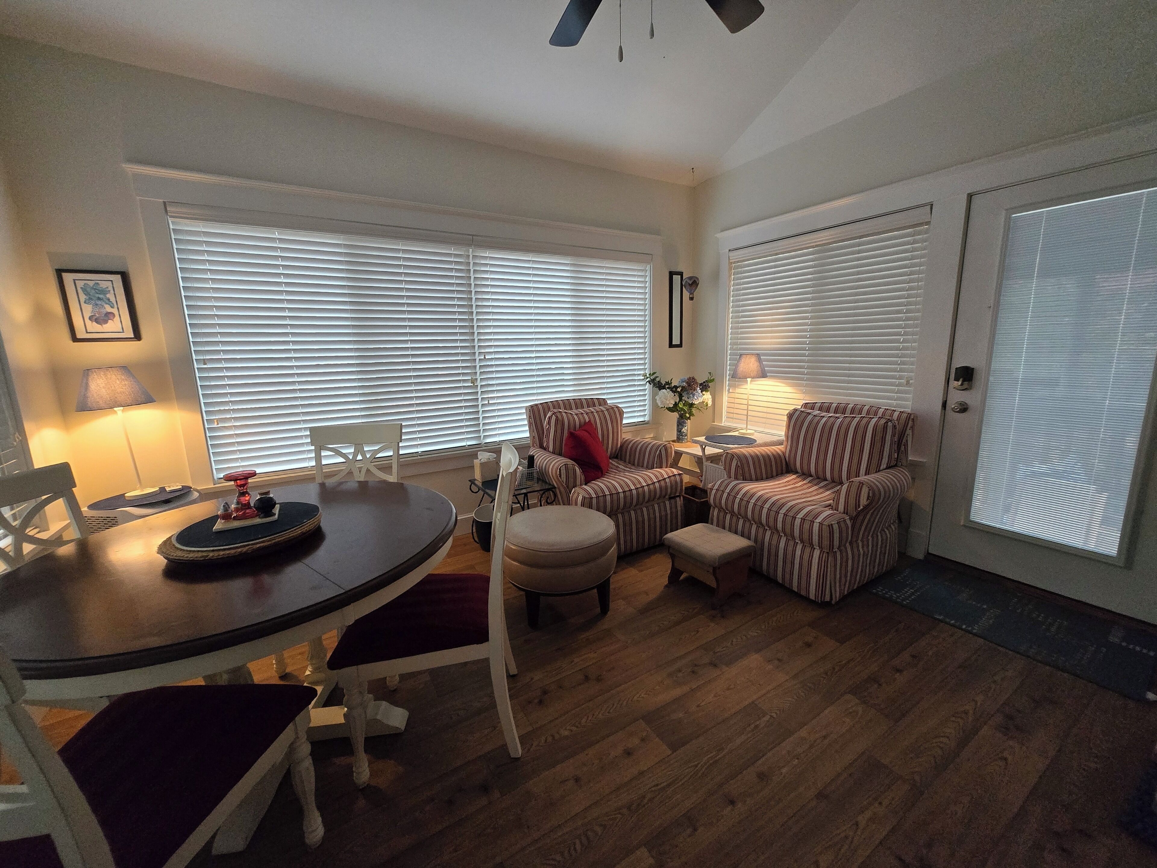 A living room with a dining table, striped armchairs, a sofa, and a lamp.