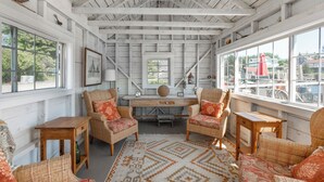 A room with wicker furniture, a wooden desk, and large windows. - Gardenwalk Crest, Elevated Harbor Views, Deck and Village Setting (Port Clyde)
