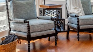 A corner seating area with two upholstered chairs, a small table, and a lamp. - Gardenwalk Crest, Elevated Harbor Views, Deck and Village Setting (Port Clyde)