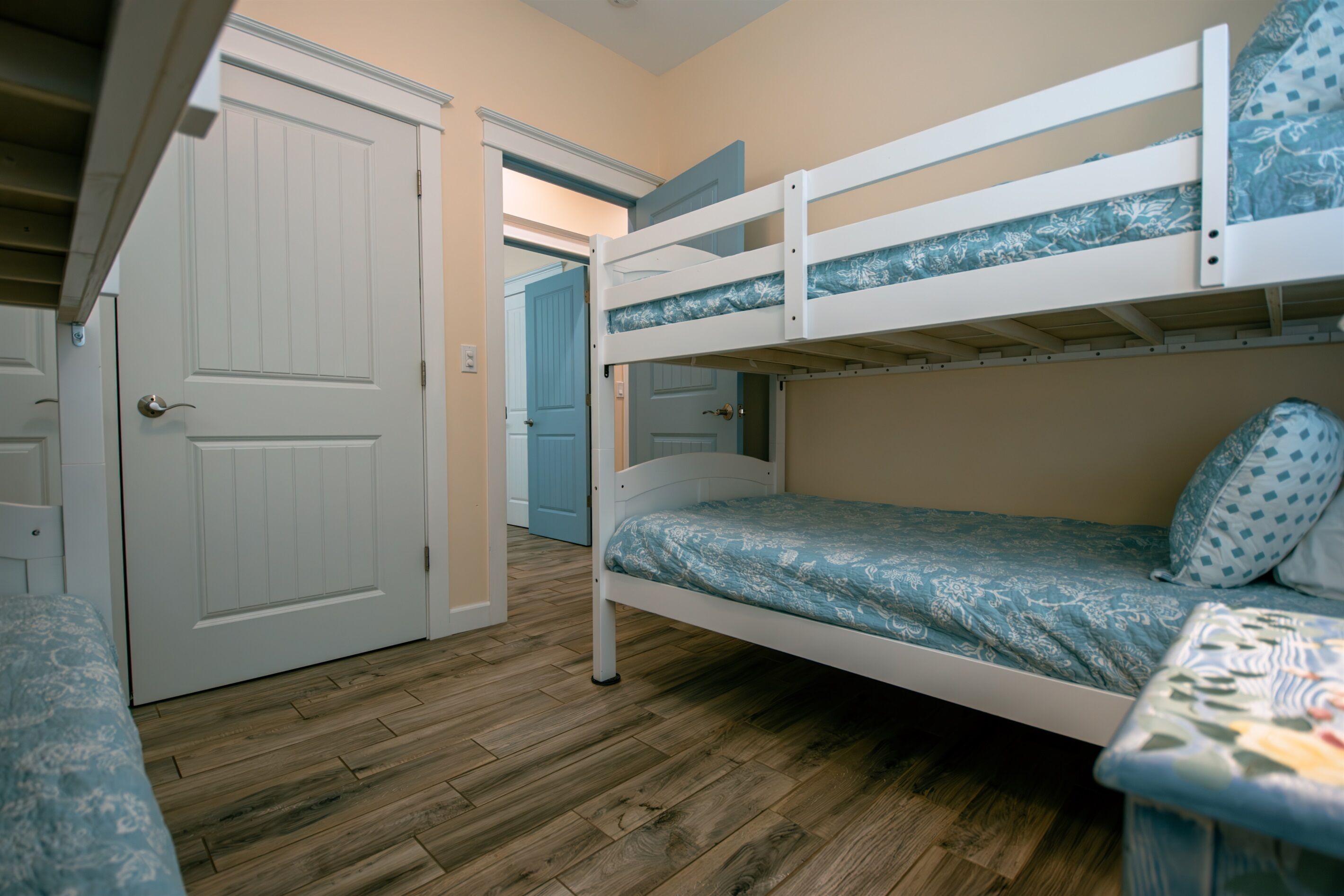 A bunk bed with a patterned mattress, a wooden floor, and a white door in a room.