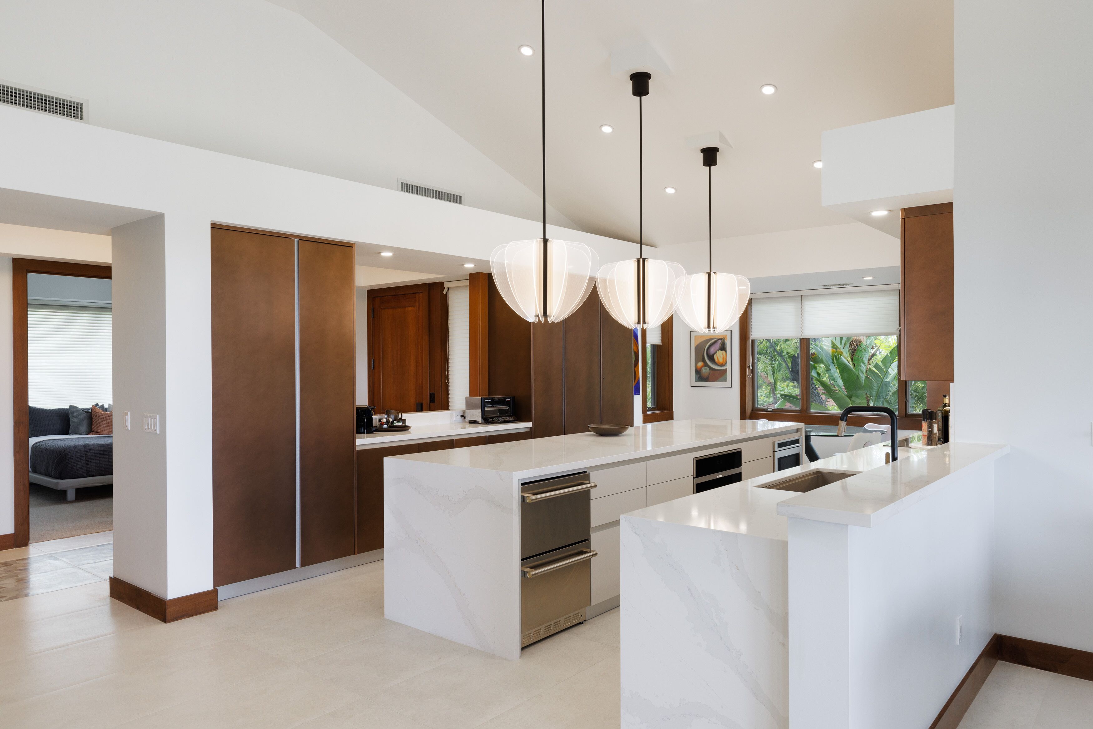 A modern kitchen with a central island, built-in appliances, and pendant lighting.