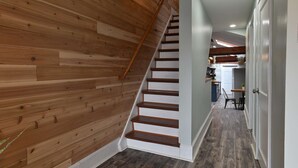 A wooden staircase leading to a kitchen area with a dining table and chairs.