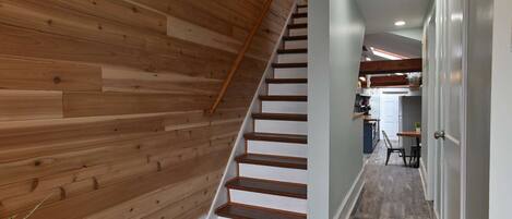 A wooden staircase leading to a kitchen area with a dining table and chairs.