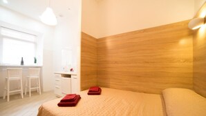 A hotel room with a bed, a desk, two chairs, and a window. - Smart Apartment Teodora 5a (Lviv)