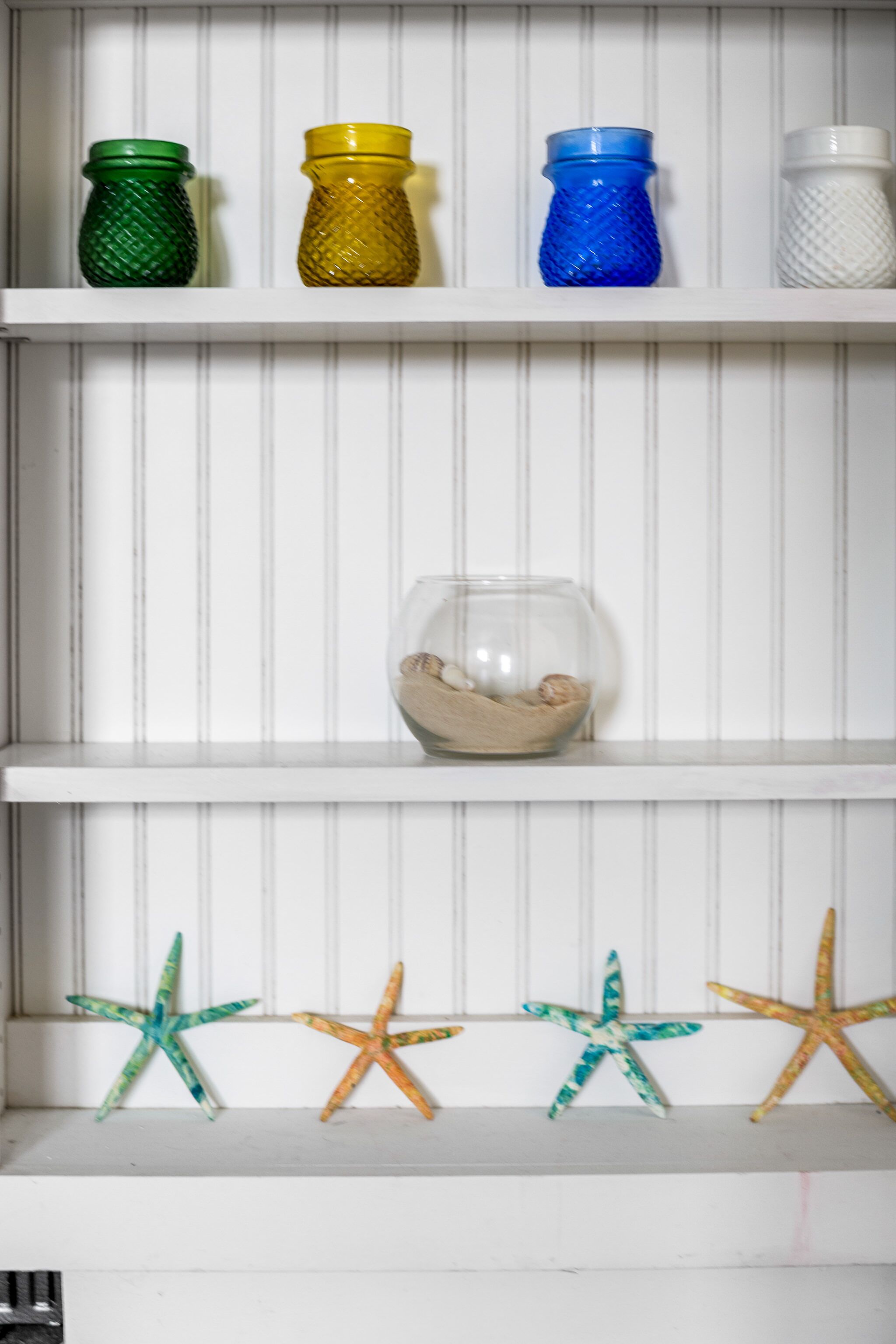 A shelf with colorful glass bottles and starfish decorations.