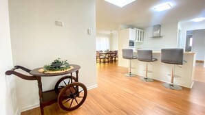 Une cuisine moderne avec des armoires blanches, une hotte en acier inoxydable et un coin repas comprenant une table ronde et des chaises.