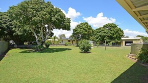 Un jardin bien entretenu avec une pelouse, un petit arbre et un bâtiment comprenant un garage.