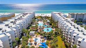 Un resort con varias construcciones, un área de piscina central y vista al mar.