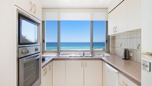 A kitchen with a view of the ocean, a built-in oven, a sink, and a coffee maker. - Kirra Gardens 17 - Kirra Point Beachfront (Coolangatta)