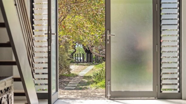 Een modern interieur met een glazen deur die uitkomt op een tuin.