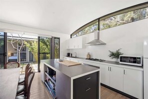 Una cocina moderna con una isla grande, armarios blancos y vistas amplias a través de ventanas.