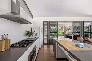 A modern kitchen with a gas stove, a microwave, and a wooden countertop.