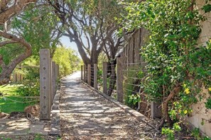 Un sendero bordeado de árboles y una cerca, que lleva a un edificio.