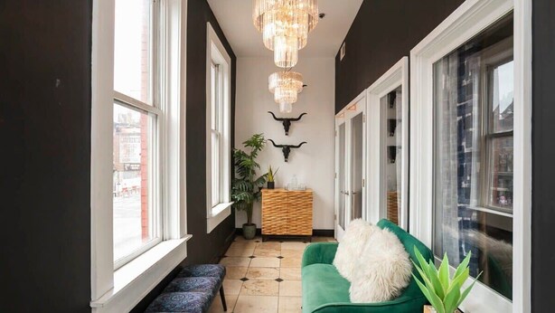 A hallway with a green sofa, a bench, a wooden cabinet, and a bull's head decoration. - Loft Over Broadway Strip (Nashville)