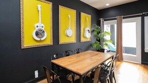 A dining area with a wooden table and black chairs, framed by a black wall with three framed guitars. - Loft Over Broadway Strip (Nashville)