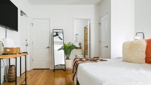 A bedroom with a bed, a mirror, a TV, and a desk with a plant. - Loft Over Broadway Strip (Nashville)