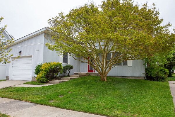 A single-story house with a red door, a garage, and a well-maintained lawn.