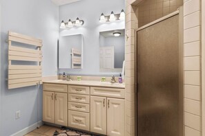 A bathroom with a double sink vanity, a mirror, and a towel rack.