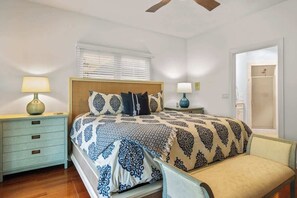 A bedroom with a bed, nightstands, a chair, and a ceiling fan.