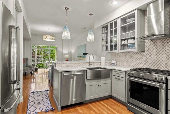 A modern kitchen with stainless steel appliances, a built-in oven, and a large island with a sink.