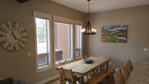 Un coin repas avec une table et des chaises en bois, une grande horloge murale et un tableau.