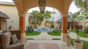 A courtyard with a stone bench, a wicker sofa, and a small fountain. - Breakfast Included w/pool 5rooms/5bath for 15 (Centro)