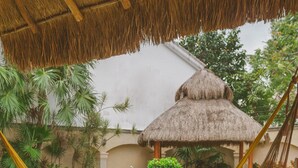A hammock in a garden area with a pool and a thatched-roof structure in the background. - Breakfast Included w/pool 5rooms/5bath for 15 (Centro)