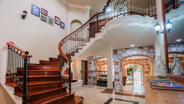 A grand staircase with wooden steps and black railings, leading to an upper floor. - Breakfast Included w/pool 5rooms/5bath for 15 (Centro)