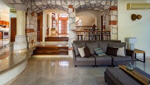 A spacious living area with a stone archway, a sofa, and a wooden coffee table. - Breakfast Included w/pool 5rooms/5bath for 15 (Centro)