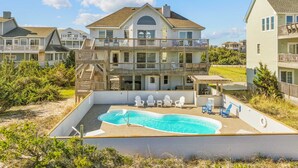 A multi-story residential building with a swimming pool and outdoor seating. - Oceanfront Home w/ Pool, Hot Tub, Game Room, Tiki Bar, Community Pool and Tennis (Waves)