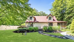 A two-story house with a red roof, a front porch, and a well-maintained lawn. - Peaceful Lakefront Home with Amazing Outdoor Space (Pullman)
