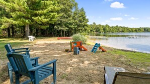A lakeside outdoor area with Adirondack chairs, a play structure, and a canoe. - Peaceful Lakefront Home with Amazing Outdoor Space (Pullman)