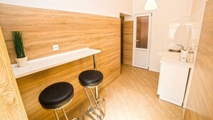 A modern kitchen with wooden accents, a white countertop, and two black bar stools. - Smart Apartment Teodora 5b (Lviv)
