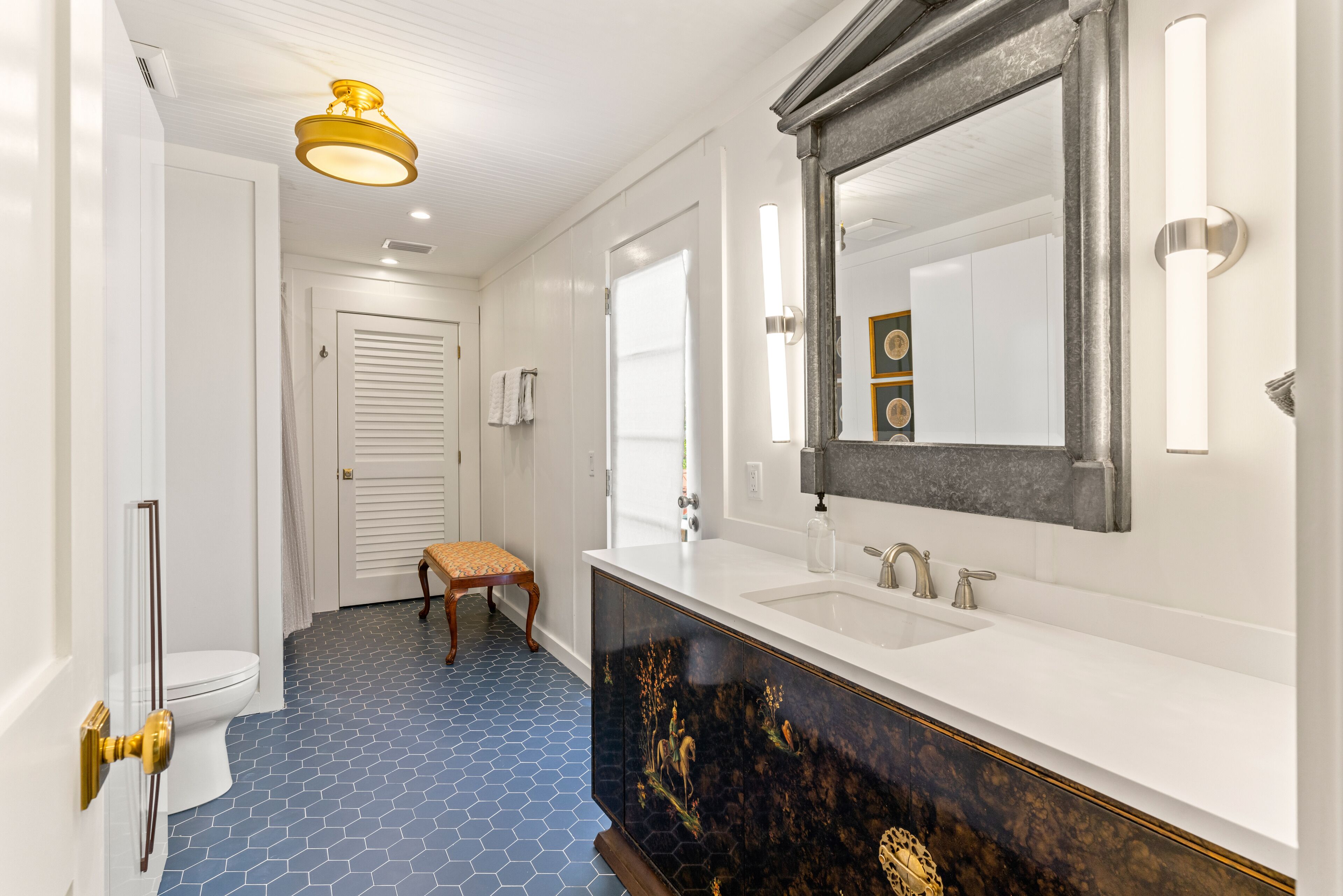A bathroom with a white sink, a large mirror, and a blue hexagonal floor pattern.