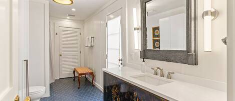 A bathroom with a white sink, a large mirror, and a blue hexagonal floor pattern.