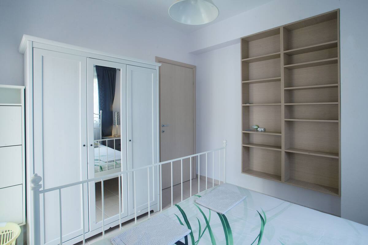 Un dormitorio con cama, armario, estantería empotrada y cuna.