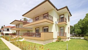 A two-story residential building with a flat roof, balconies, and a well-maintained lawn. - Olive Village (Sithonia)