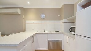 A compact kitchen with white cabinets, a stainless steel sink, a microwave, and a dishwasher.