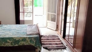 Une chambre à coucher avec un lit, un lustre, une porte-fenêtre coulissante et une vue sur l’extérieur.