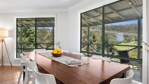 A dining area with a wooden table, white chairs, and a bowl of lemons.