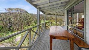 A wooden deck with a table and benches, overlooking a forested landscape.