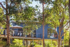 Una casa moderna con una terrazza, posti a sedere all'aperto e rigogliosa vegetazione.