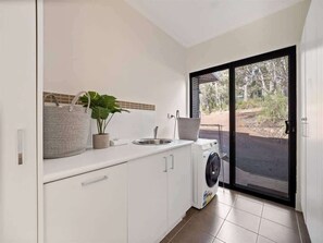 Una cocina compacta con lavadora, un lavabo y una planta en maceta.