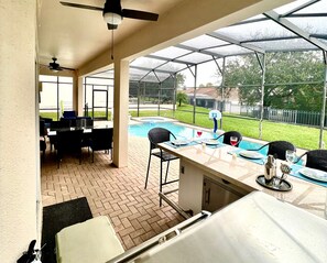A covered patio area with a pool, outdoor seating, and a ceiling fan.