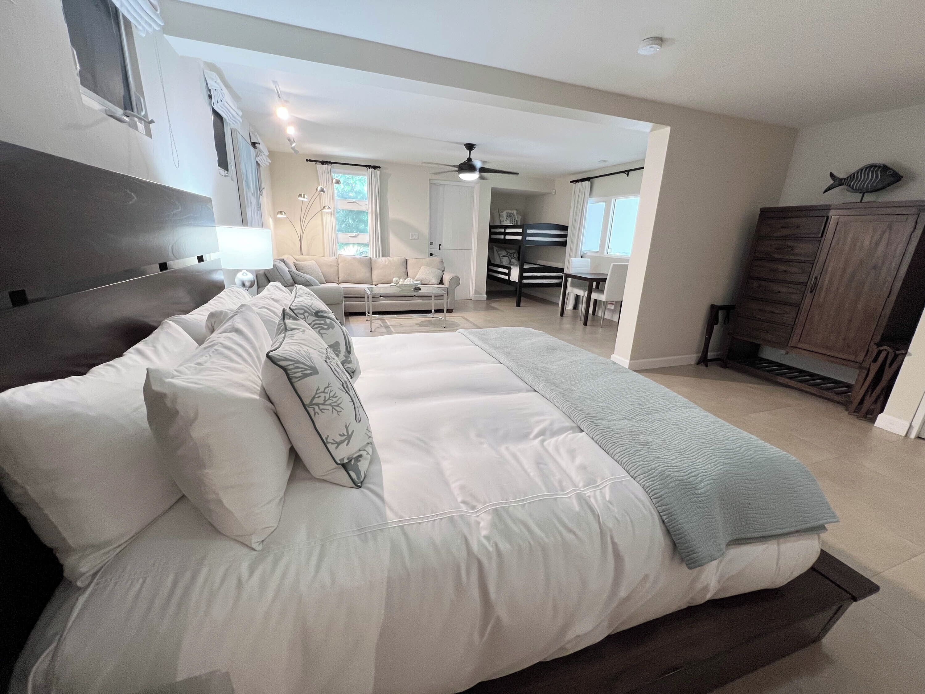 A spacious bedroom with a large bed, a wooden headboard, a desk, and a wardrobe.