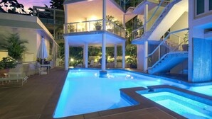 A swimming pool with a glass balustrade, surrounded by lounge chairs and potted plants. - The Hill Villa 2 Port Douglas (Port Douglas)
